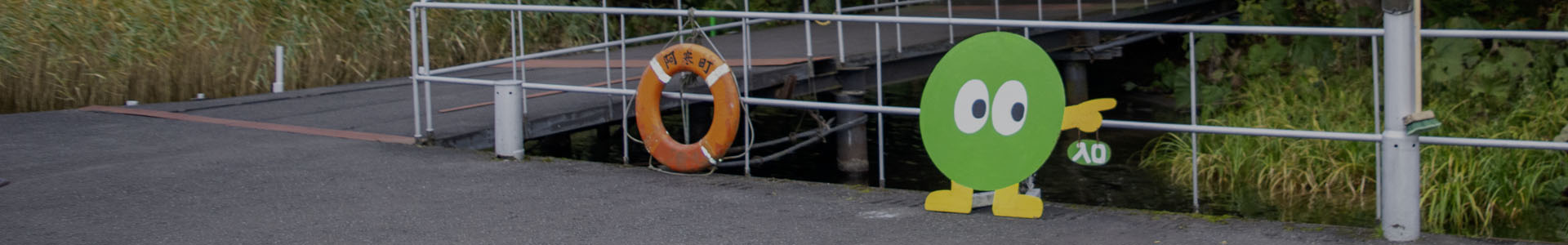 Marimo character sign welcomes visitors to Churui Island at Lake Akan, Japan, directing guests from the ferry dock to the Marimo Exhibition Center.