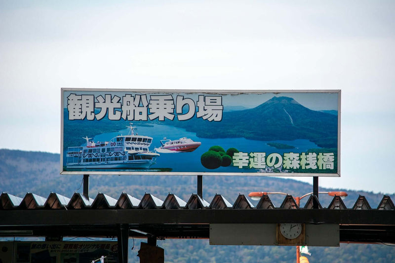 Sign at the Lake Akan ferry terminal in Hokkaido, Japan, promoting Marimo moss ball sightseeing cruises to Churui Island.