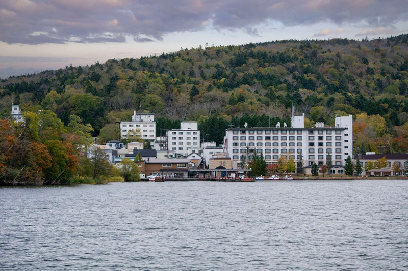 Hotels (ryokan and hoteru) and lakeside businesses along the scenic shores of Lake Akan in Hokkaido, Japan, as seen from the Marimo ferry.