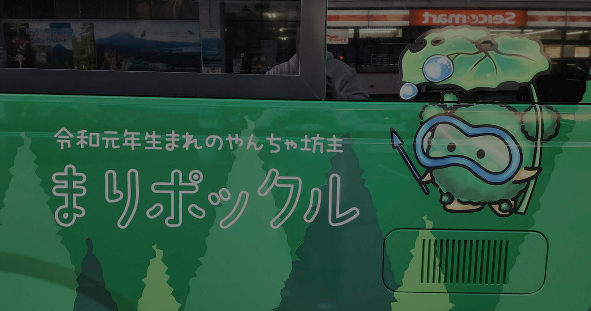 Marimo mascot on a green tourist bus in Kushiro, Japan, promoting Lake Akan’s famous moss balls.