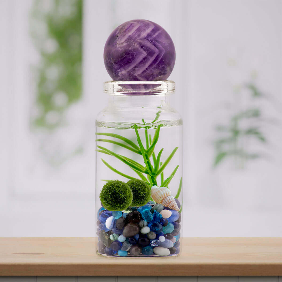 Amethyst sphere atop a terrarium, a purple gemstone known for tranquility.