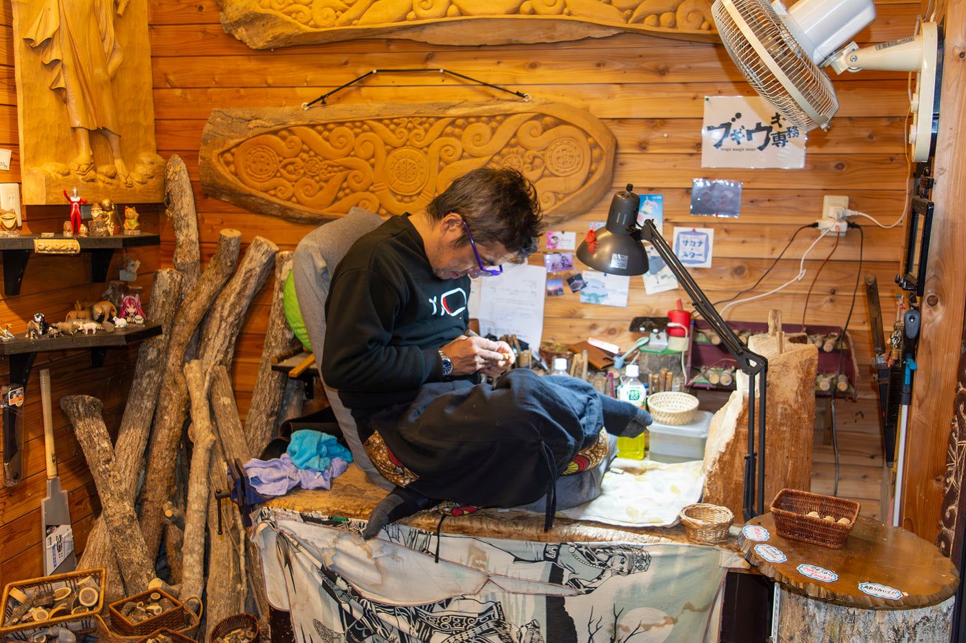 An Ainu woodcarver deeply focused on crafting a traditional wooden sculpture in their workshop, surrounded by natural materials, tools, and intricate carvings that reflect the rich cultural heritage of the Ainu people.