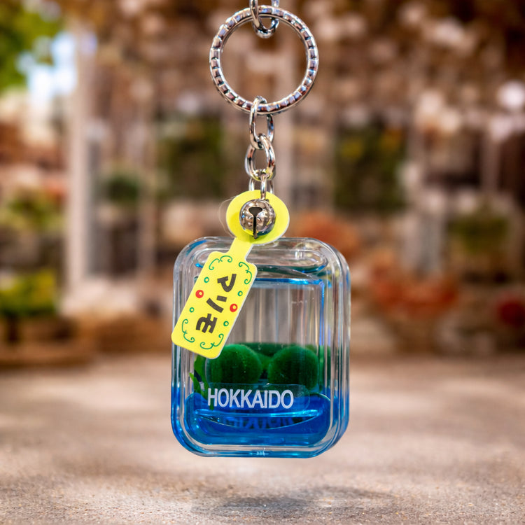 Blue marimo moss ball keychain with Hokkaido label hanging display style Lake Akan Japan souvenir