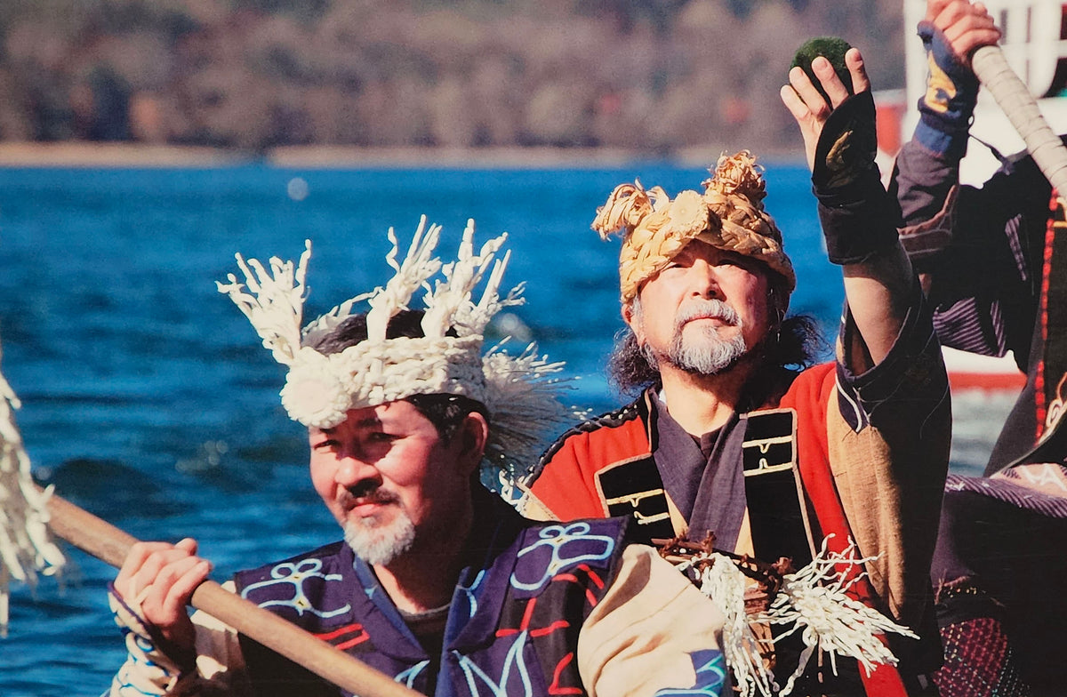 Ainu community members in traditional ceremonial attire participate in a sacred ritual on Lake Akan, symbolically returning marimo moss balls to the water as a gesture of respect, renewal, and gratitude for nature’s gifts, honoring the spiritual connection between the Ainu people and the lake.