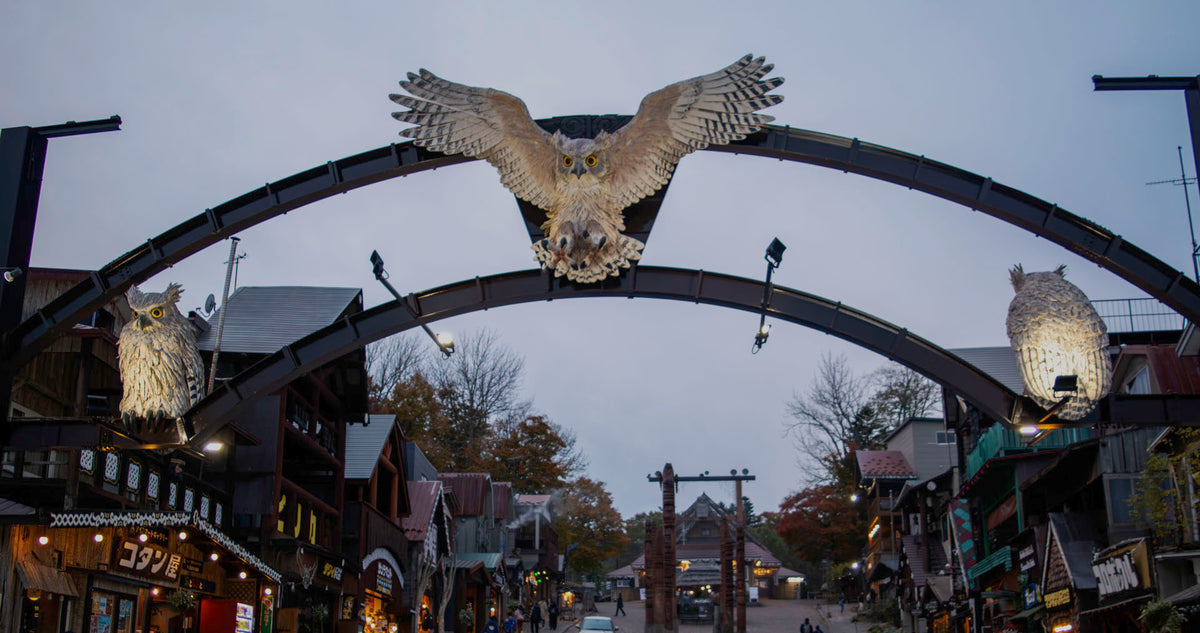 Entrance gate to Akanko Onsen Village featuring three illuminated owls, symbolizing the Ainu guardian spirit kotan kor kamuy. The central owl in flight honors the Ainu’s sacred connection to nature and protection of their homeland.