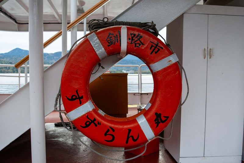 A red life preserver with Japanese writing hangs on the ferry deck at Lake Akan.